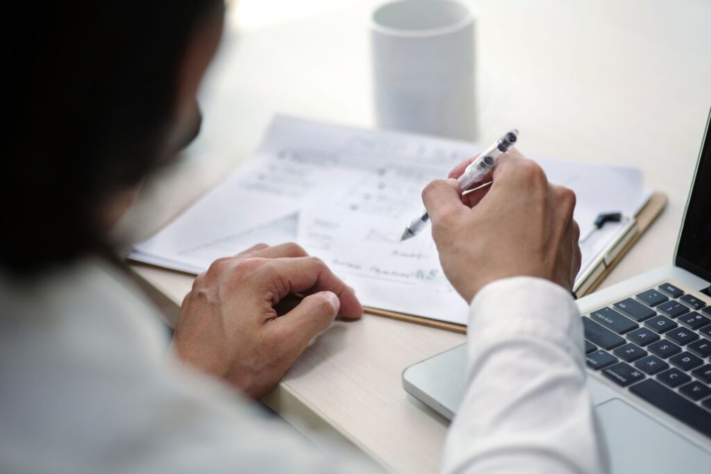 young-asian-businessman-sitting-in-the-office-writing-a-business-plan-with-laptop-and-coffee-cup-958629584-df395095d88143cfadd319e1a2219df8